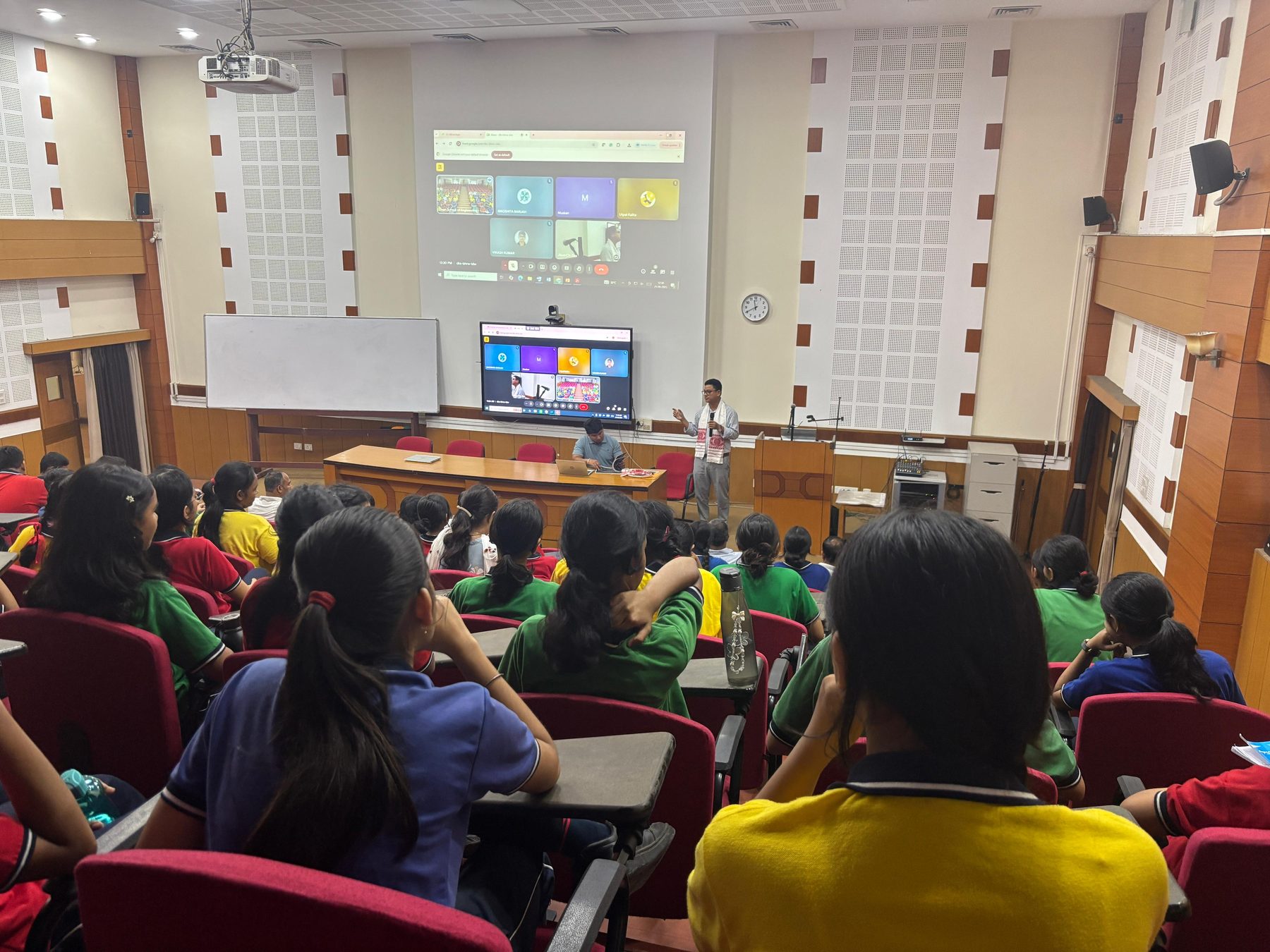 Dr. Rachan Daimary addressing a full auditorium of school students